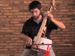 a cello made from an oil can and landfill trash